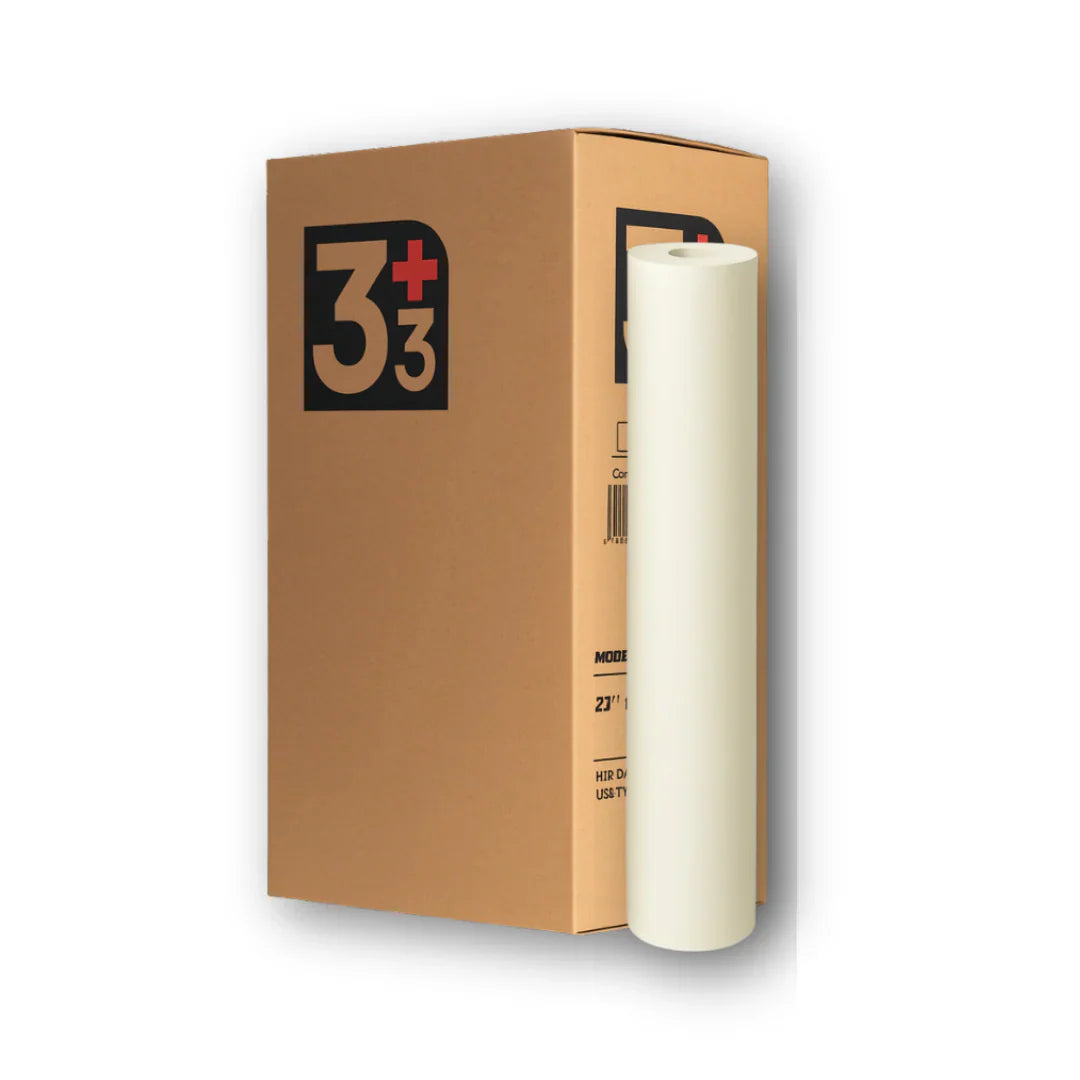 Upright white smooth massage table paper roll standing beside its branded 3+3 brown cardboard shipping box on a white background.