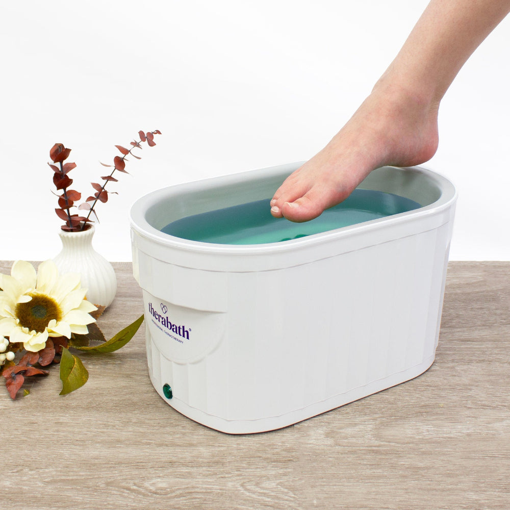 The Therabath unit being used for a paraffin foot treatment, illustrating the deep tank design that accommodates larger extremities.
