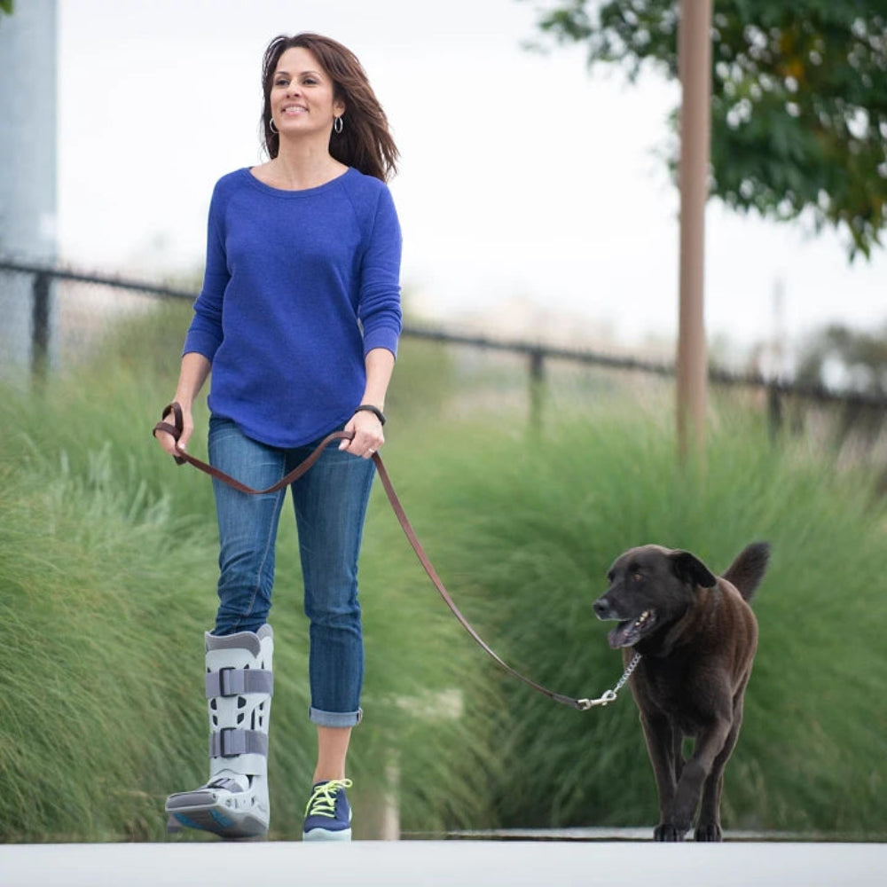 A person walking their dog while wearing the AirSelect Elite boot, highlighting how the lightweight design allows for continued daily activities during recovery.