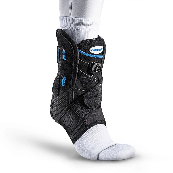 Three-quarter view of a black Aircast AirSport Plus ankle support brace with blue accents worn over a white sock against a plain white background.