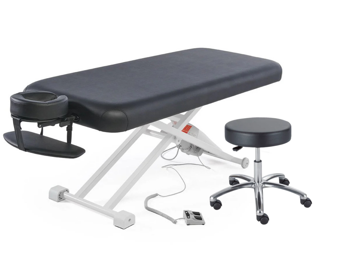 Black flat top electric massage table with attached face cradle, foot pedal control, and matching black hydraulic rolling stool on a white background.