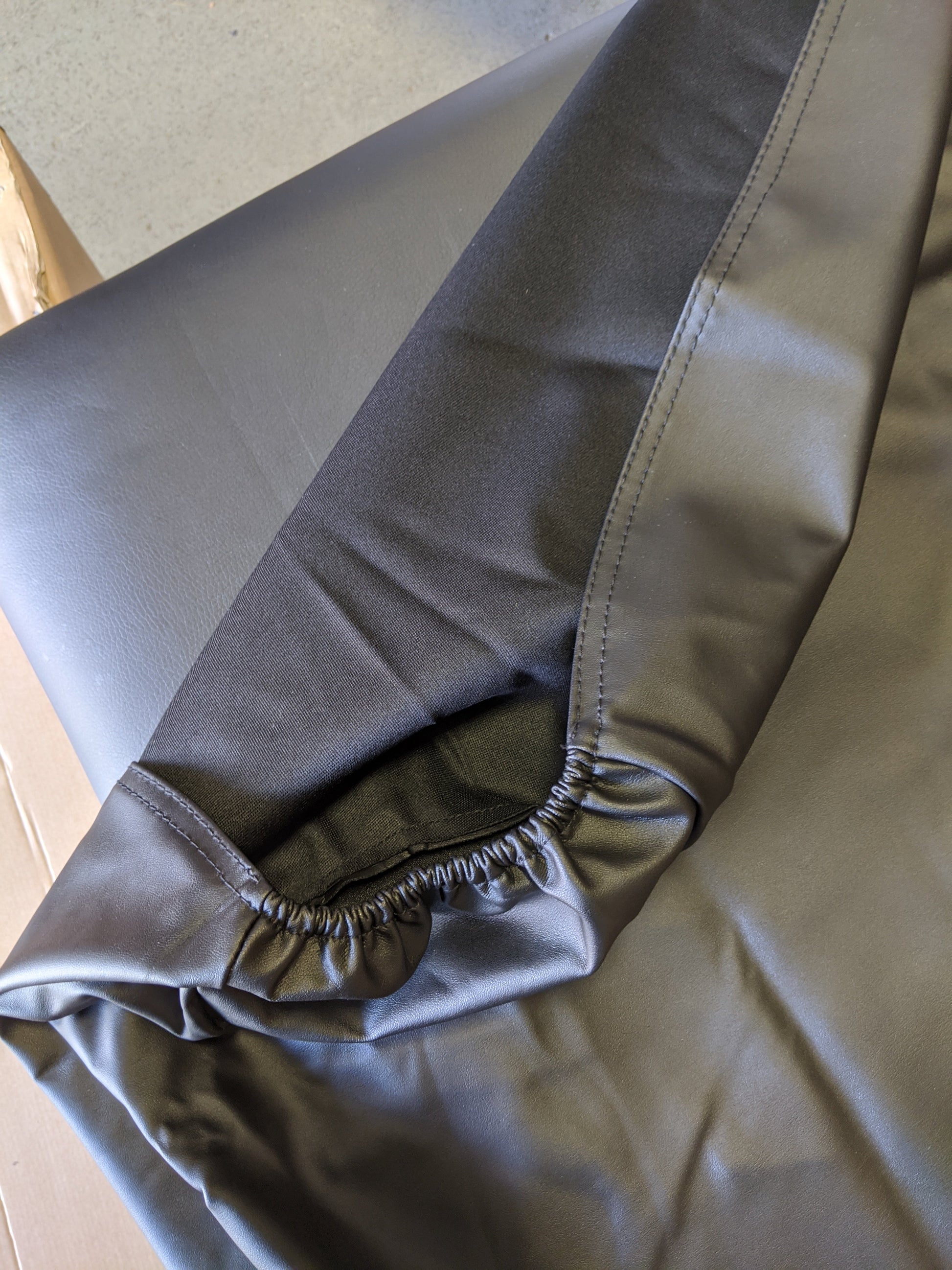 Close up view of elastic hem and stitching on black PU vinyl massage table cover