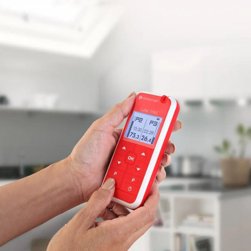 The red Cefar TENS unit shown in a home setting, illustrating its suitability for both clinical use and patient self-care.