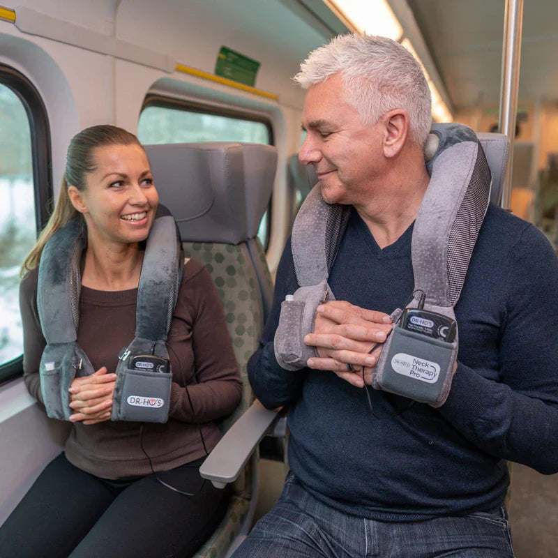 Man and woman wearing DR-HO's Neck Therapy Pro devices while sitting on a train