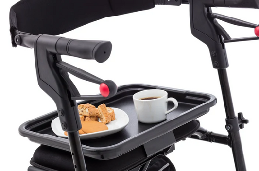 Black plastic tray attachment mounted on a Nexus 3 rollator holding a cup of coffee and a plate with snacks on a white background.