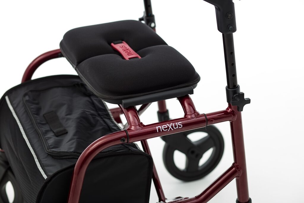 Detail view of the Burgundy Red NeXus 3 rollator, highlighting the sleek metallic finish and durable seat pull strap for easy folding.