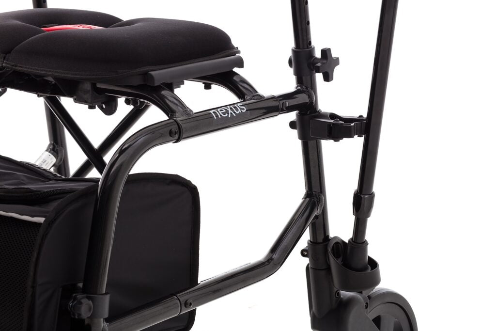Close-up view of a black cane holder attachment clip mounted on the frame of a Nexus rollator walker on a white background.