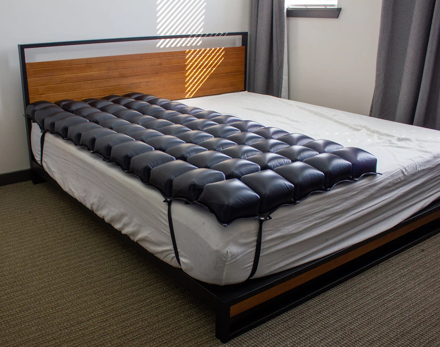 The PRODIGY mattress overlay shown in a home bedroom setting, illustrating how easily it integrates into existing bedding for long-term pressure management.