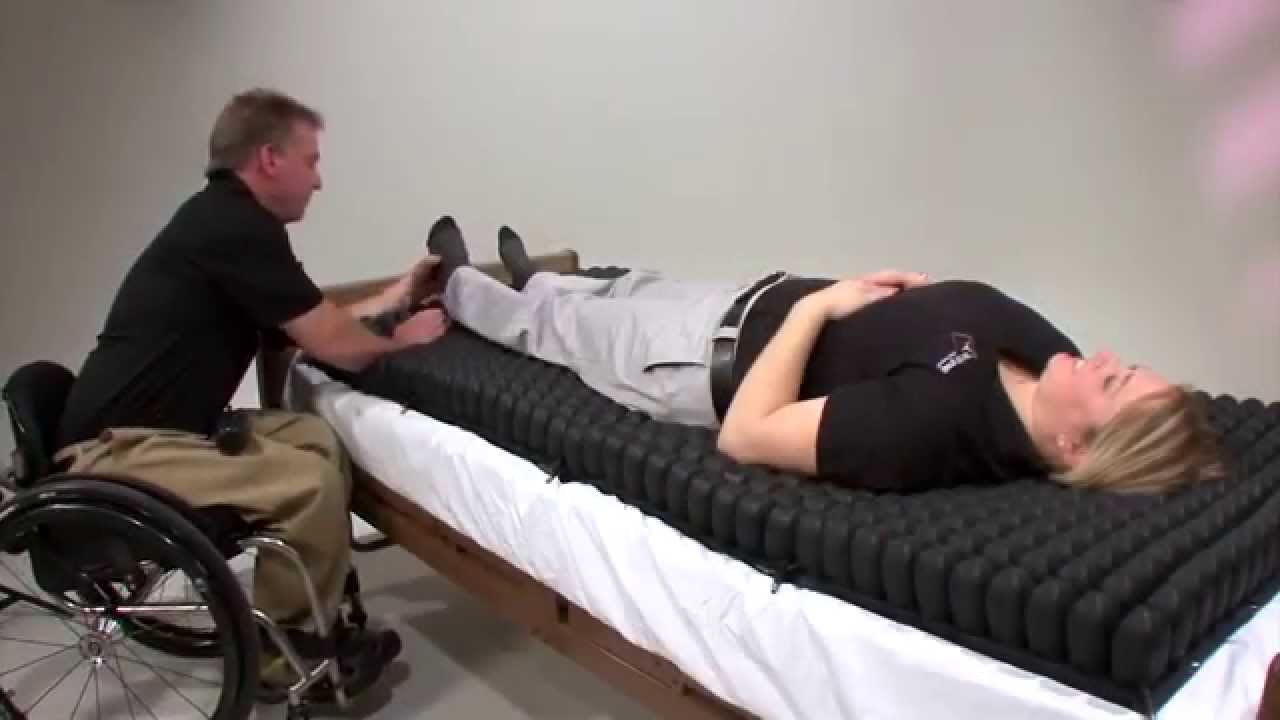 A person lying on the mattress overlay, demonstrating the effective immersion and support provided to the torso and hips to prevent tissue breakdown.