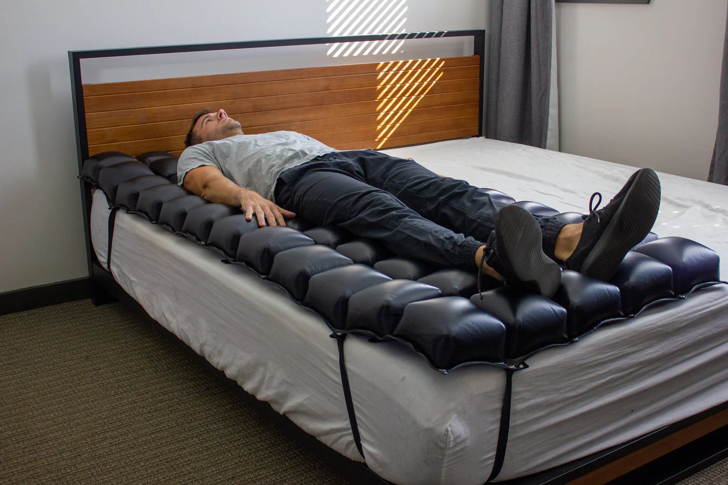 A person lying on the mattress overlay, demonstrating the effective immersion and support provided to the torso and hips to prevent tissue breakdown.