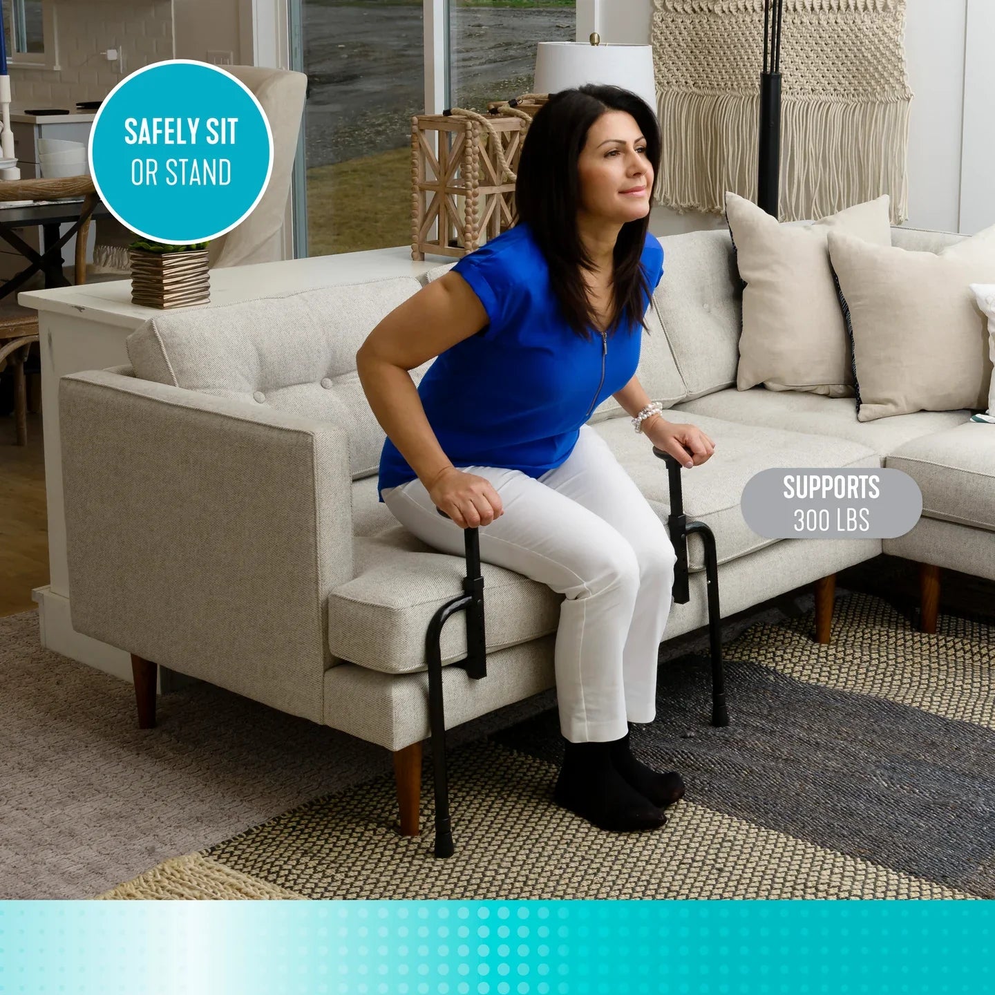 Stander EZ Stand-N-Go couch assist standing frame placed on a light beige sofa showing adjustable width and padded grab handles against a white background.