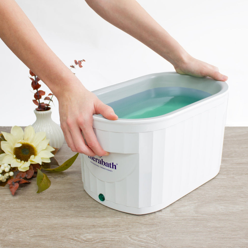 A user immersing their hand into the warm paraffin wax of the Therabath TB6, demonstrating the deep-tank design used for arthritis and joint pain relief.