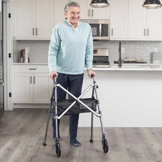 The rollator positioned next to an armchair, providing a stable frame for a user to safely stand up or sit down.
