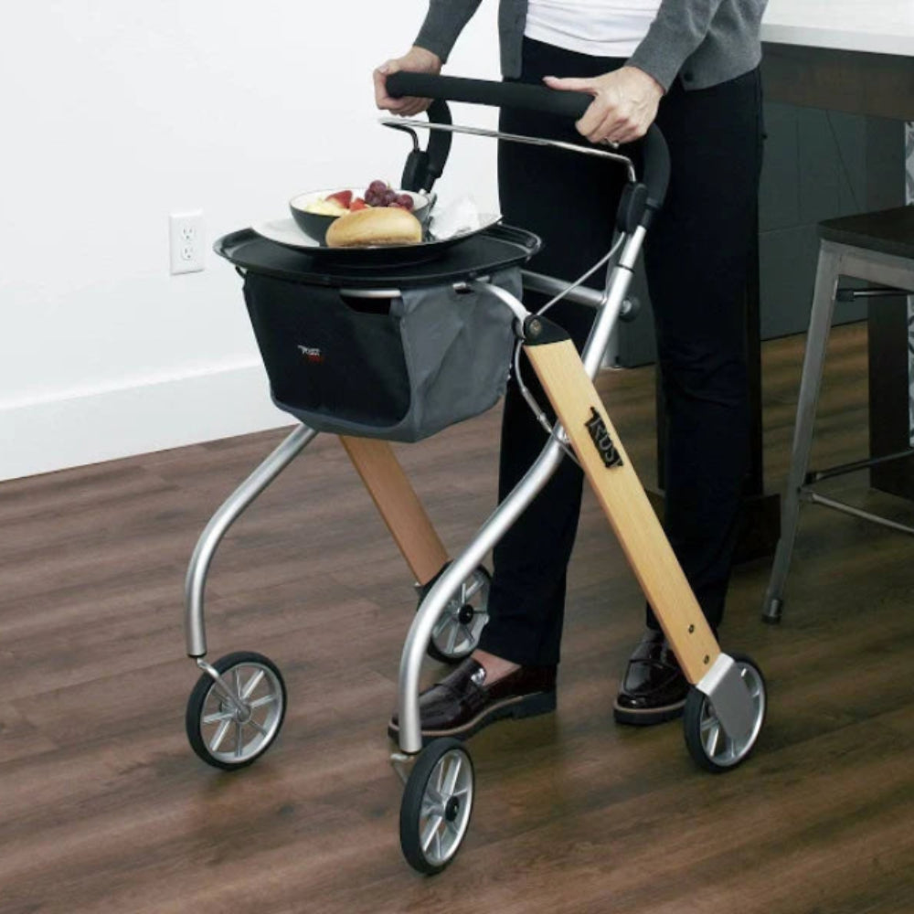 A direct front view of the beech and silver Let's Go Indoor Rollator, showcasing the single-hand brake bar and the black storage bag.